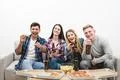 The four happy people watch tv with a pizza and a beer on the white backgroun Photo
