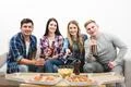 The four happy people watch tv with a pizza and a beer on the white backgroun Photo