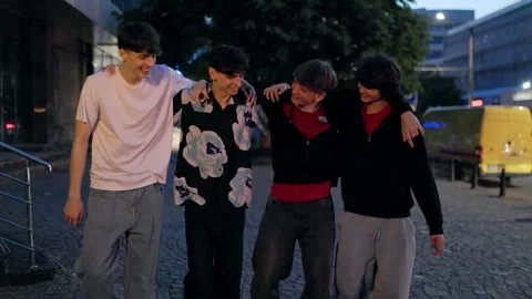 Four happy young men gesturing and laughing on a city street at night. Vidéo 335192064