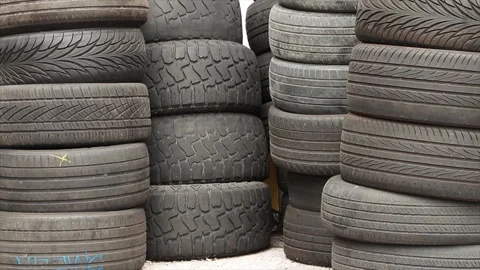 Four high stacks of worn and faded used car tires next to one another Stock Footage 246610888
