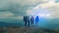 The four hikers are standing on the mountain top 4k or 4k+ Resolution