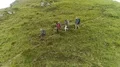 The four hikers with backpacks walking down on a mountain 4k or 4k+ Resolution