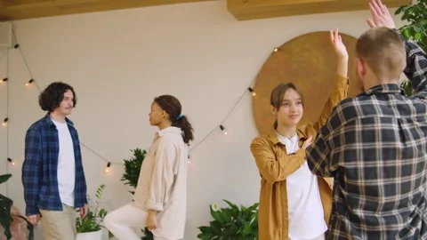 Four individuals interact in a spacious indoor area filled with plants. They eng Stock Footage 346148037