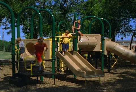 Four kids using playground equipment in a park Stock Footage 86884846