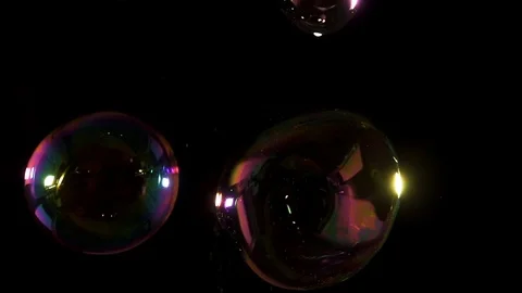 Four large bubbles refracting colorful light in the darkness Stock Footage 77134380