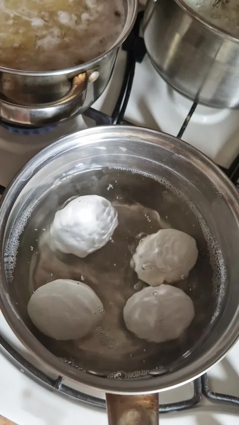 Four Large White Dumplings Boiling in a Stainless Steel Pot on Stovetop Stock-Footage 339079685