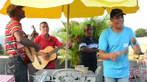 Four latino men musicians are playing guitar, small drum and maracas, singing Stock Footage
