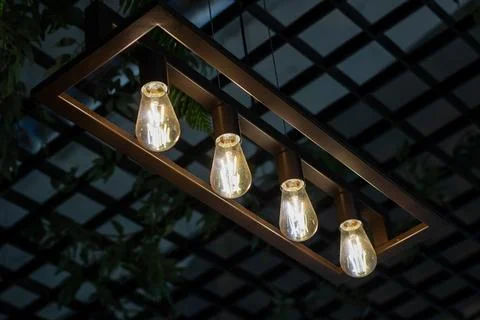 Four light bulbs are elegantly hanging down from a wooden frame Foto stock