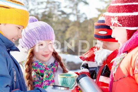 Four little children pouring tea into cups in winter outdoors Stock Photos