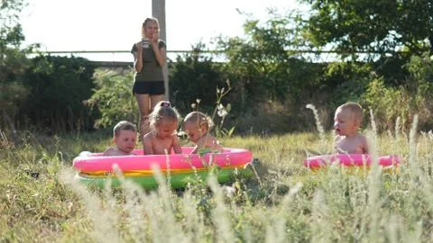 Four little kids in the inflatable pool on the meadow playing with water Foto stock