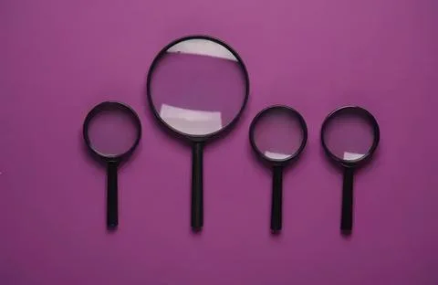 Four magnifying glasses of different sizes on purple background Stock Photos