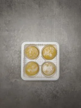 Four mango mochi resting in plastic container on marble countertop Stock Photos