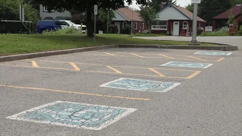 Four marked empty handicap parking spaces in parking lot with cars passing Stock Footage 247749127