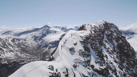Four men walking on a sharp mountain ridge with skis on their back Stock Footage 99738301