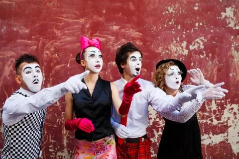Four mimes looking aside on the background of a red wall. Stock Photos