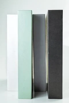 Four minimalist decorative books in white, mint green, grey, and black stan.. Stock Photos