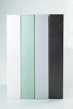 Four minimalist decorative books in white, mint green, grey, and black stan.. Stock Photos