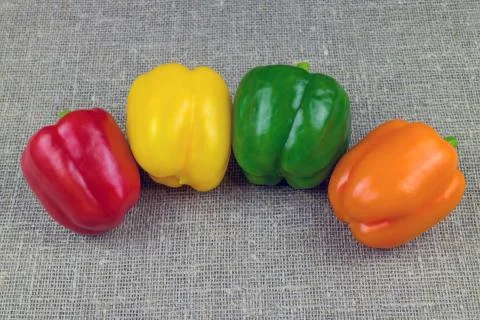 Four multi-colored bell peppers, sweet paprica on fabric Stock Photos