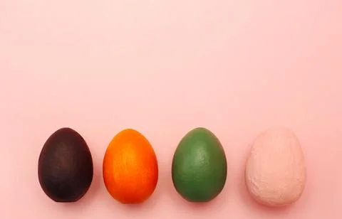 Four multi-colored decorative eggs on a pink background. Stock Photos