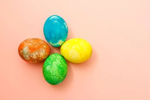 Four multi-colored Easter eggs on pink background top view, space for text. C Stock-Fotos