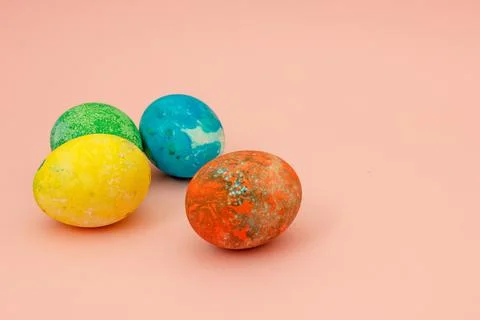Four multi-colored Easter eggs on pink background top view, space for text. C Stock Photos