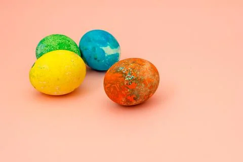 Four multi-colored Easter eggs on pink background top view, space for text. C Foto stock