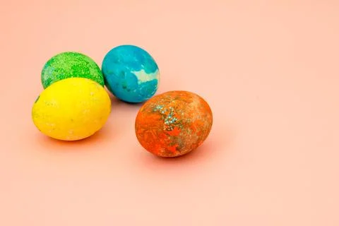 Four multi-colored Easter eggs on pink background top view, space for text. C Stock Photos
