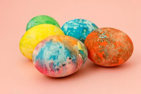 Four multi-colored Easter eggs on pink background top view, space for text. C Stock Photos