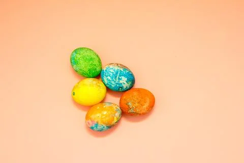 Four multi-colored Easter eggs on pink background top view, space for text. C Stock Photos
