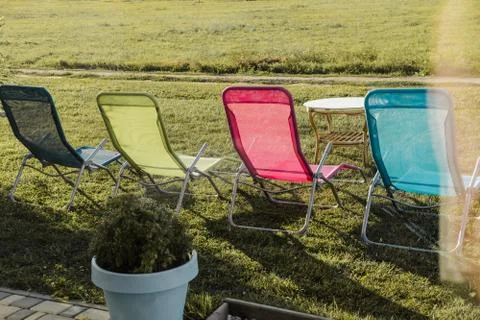 Four multi-colored sunbeds are standing outside on green grass. The concept of Stock Photos