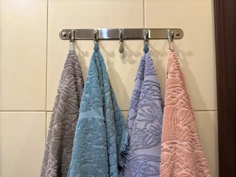 Four multi-colored towels on a silver-colored steel hanger Stock Photos
