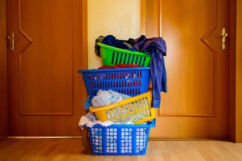 Four multicolored baskets with washed laundry are standing one on another in Stock Photos
