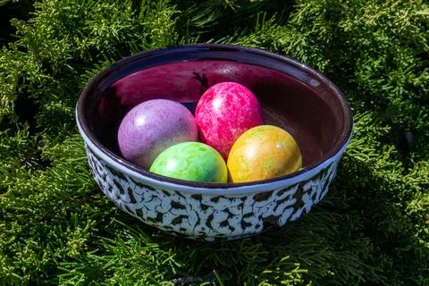 Four multicolored bright easter eggs in ceramic bowl Stock Photos