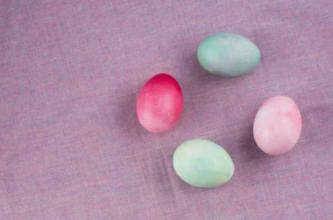 Four multicolored painted Easter eggs lilac tablecloth. holiday easter greeti Stock Photos