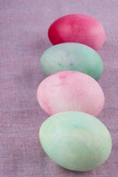 Four multicolored painted Easter eggs lilac tablecloth. holiday easter greeti Stock Photos
