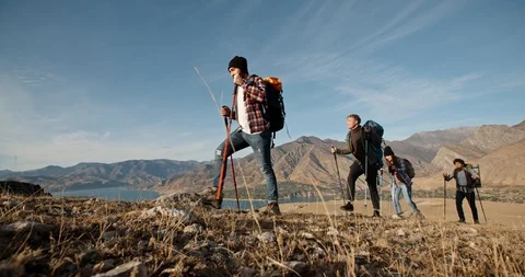 Four multiethnic friends going on hiking adventure, trekking in mountains Stock Footage 129338574