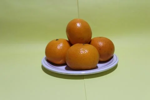 Four oranges on light green background Stock Photos