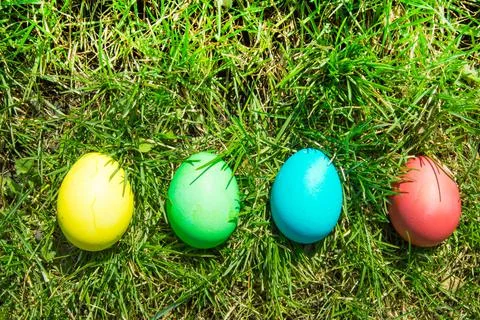 Four painted and decorative Easter eggs in the grass. Top view, copy space Stock Photos
