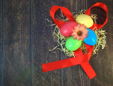 Four painted Easter eggs in a nest of straw with a flower in the center, lyin Stock Photos