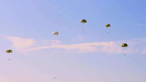 Four parachutists drift gracefully under green canopies, descending from Stock Footage 286345447