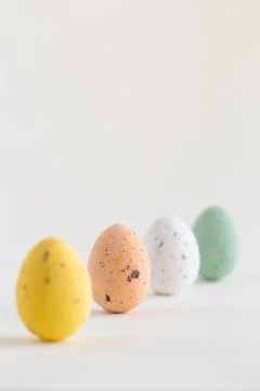 Four pastel colored chocolate Easter eggs, one pink egg sharp, on white backg 写真素材