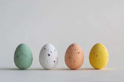 Four pastel colored chocolate Easter eggs in a row, on white background with Stock Photos