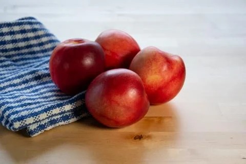 Four peaches on the table with tablecloth. Stock Photos