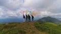 The four people with color smoke bombs standing on a mountain 4k or 4k+ Resolution
