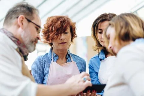 Four people in creative studio, looking at smartphone Stock Photos