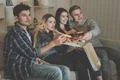 The four people eat a pizza and watch a movie on the sofa Photo