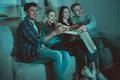 The four people eat a pizza and watch a movie on the sofa Photo