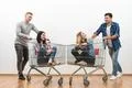 The four people fun with a shopping cart on a white wall background Photo