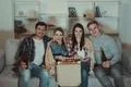 The four people with a pizza and a beer watch a movie on the sofa Photo