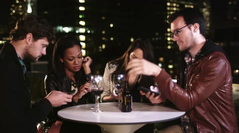 Four people sit at a table but ignore each other while they are on their phones Stock Footage 44186191